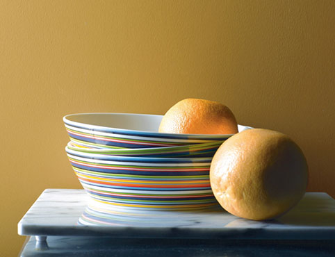 Dinner plates in variety of bright colors against yellow wall Dinner plates in variety of bright colors against yellow wall