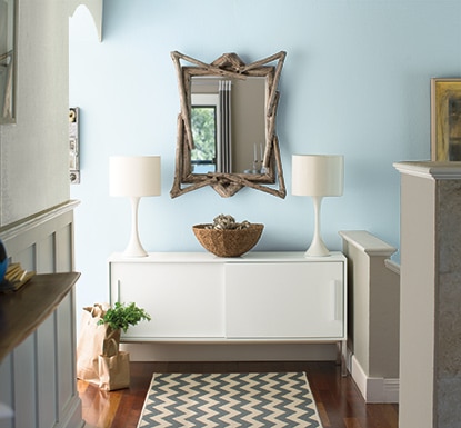 Home interior with light blue walls framed by an end table holding matching white lamps Home interior with light blue walls framed by an end table holding matching white lamps