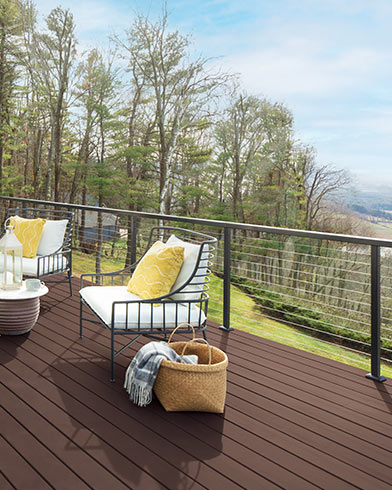 Pretty white cushioned outdoor furniture with yellow pillows and a small table on a Mahogany ES-60 Woodluxe® Solid stained deck.